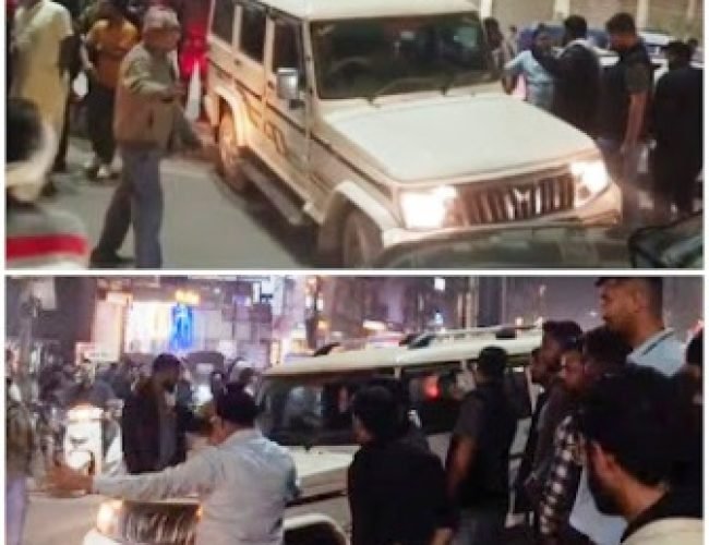 घड़ी चौक पर हादसे के बाद बोलेरो वाहन डिवाइडर पर चढ़ा हुआ, मौके पर जुटी भीड़ और यातायात पुलिस।